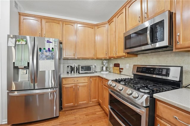 22480 W 113th St, Olathe, KS 66061 - kitchen with appliances with stainless steel finishes, light countertops, backsplash, and light wood-type flooring