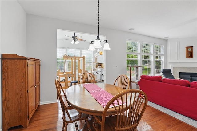 22480 W 113th St, Olathe, KS 66061 - dining space featuring light wood finished floors, a tile fireplace, a ceiling fan, a chandelier, and baseboards