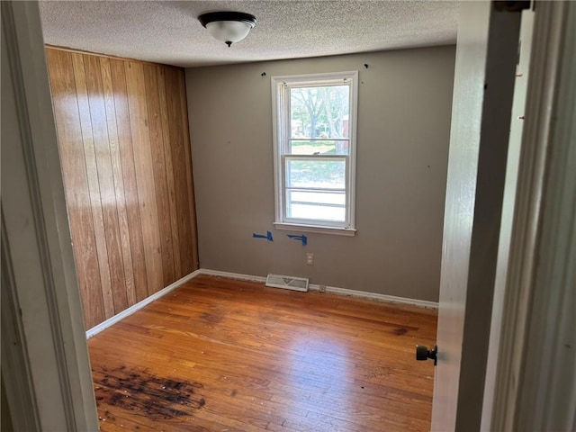 8724 N Jefferson St, Kansas City, MO 64155 - empty room with wood-type flooring, wooden walls, a textured ceiling, and baseboards