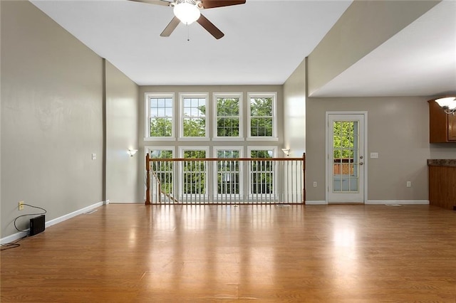 3208 Arbor Lake Dr, Saint Joseph, MO 64506 - unfurnished living room with a ceiling fan, baseboards, wood finished floors, and a high ceiling
