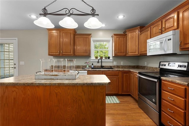 3208 Arbor Lake Dr, Saint Joseph, MO 64506 - kitchen featuring white microwave, electric stove, a sink, light wood-style floors, and a kitchen island