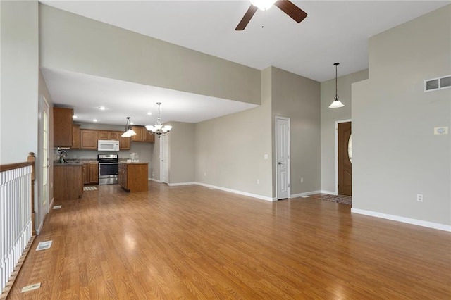 3208 Arbor Lake Dr, Saint Joseph, MO 64506 - unfurnished living room with ceiling fan, a chandelier, baseboards, light wood-style floors, and a high ceiling