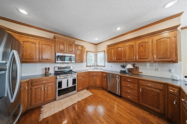 14801 W 70th St, Shawnee, KS 66216 - kitchen with stainless steel appliances, a sink, a textured ceiling, brown cabinetry, and dark wood finished floors