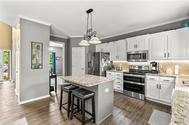 9820 N Donnelly Ave, Kansas City, MO 64157 - kitchen featuring appliances with stainless steel finishes, tasteful backsplash, a kitchen island, crown molding, and white cabinetry