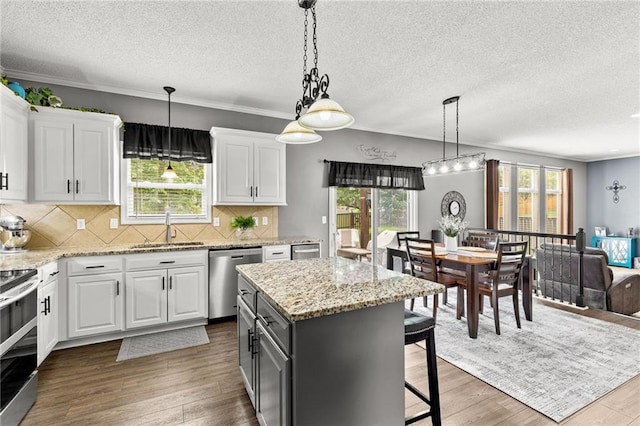9820 N Donnelly Ave, Kansas City, MO 64157 - kitchen featuring appliances with stainless steel finishes, a sink, white cabinetry, a textured ceiling, and a center island
