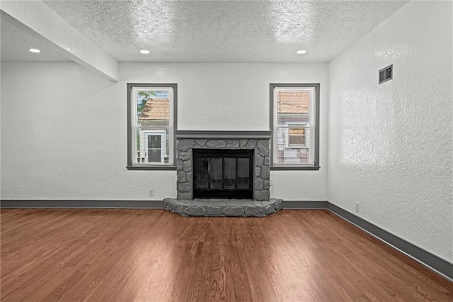 2317 S Maywood Ave, Independence, MO 64052 - unfurnished living room with a textured ceiling, a textured wall, wood finished floors, a fireplace, and baseboards