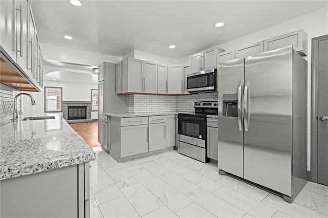 2317 S Maywood Ave, Independence, MO 64052 - kitchen with appliances with stainless steel finishes, a sink, gray cabinetry, light marble finish flooring, and recessed lighting