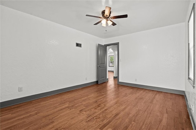 2317 S Maywood Ave, Independence, MO 64052 - unfurnished room featuring wood finished floors, a ceiling fan, baseboards, and arched walkways