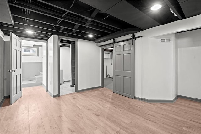 2317 S Maywood Ave, Independence, MO 64052 - basement with light wood finished floors, a barn door, stairway, and baseboards