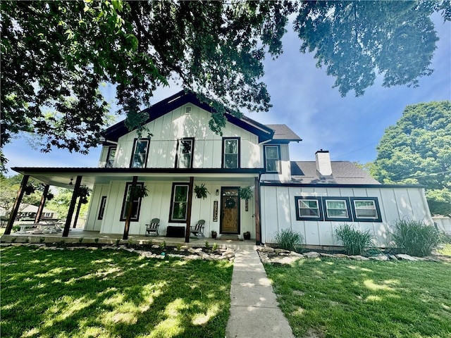 906 E Piankishaw St, Paola, KS 66071 - view of front of property featuring a porch, a front yard, board and batten siding, and a chimney