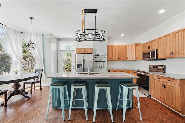 906 E Piankishaw St, Paola, KS 66071 - kitchen with appliances with stainless steel finishes, a center island with sink, dark wood-type flooring, a chandelier, and recessed lighting