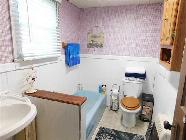 213 W 5th St, Wellsville, KS 66092 - bathroom with a garden tub, wainscoting, toilet, tile patterned flooring, and a sink