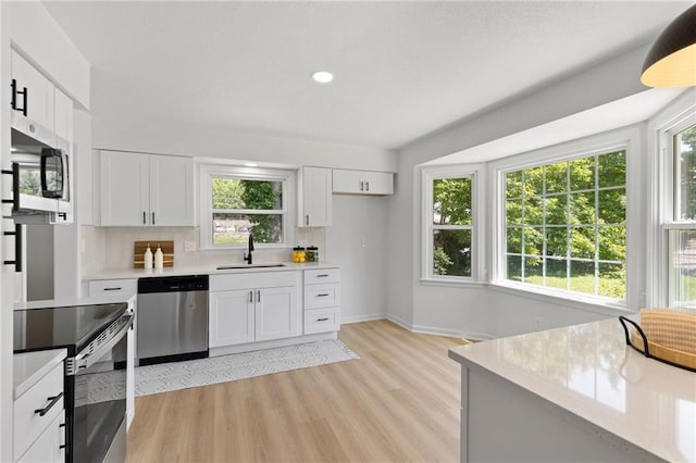 9501 Glenwood St, Overland Park, KS 66212 - kitchen featuring appliances with stainless steel finishes, a sink, light countertops, light wood finished floors, and white cabinets