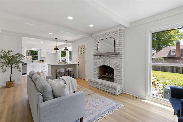 9501 Glenwood St, Overland Park, KS 66212 - living area with beamed ceiling, a fireplace, light wood-style flooring, baseboards, and recessed lighting