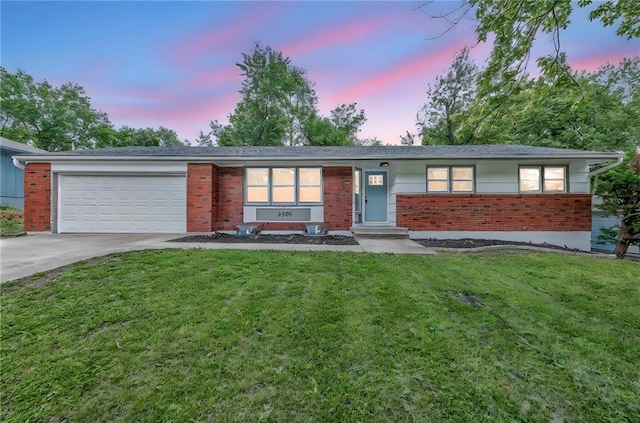 5005 S Grand Ave, Independence, MO 64055 - ranch-style house with concrete driveway, brick siding, an attached garage, and a front lawn