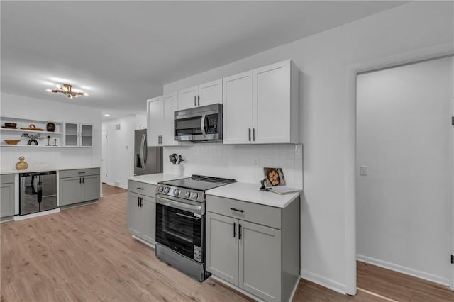 5005 S Grand Ave, Independence, MO 64055 - kitchen featuring appliances with stainless steel finishes, gray cabinets, decorative backsplash, open shelves, and light countertops