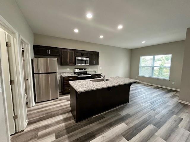 10204 Siena Dr, Peculiar, MO 64078 - kitchen with stainless steel appliances, a kitchen island with sink, light wood finished floors, recessed lighting, and a sink