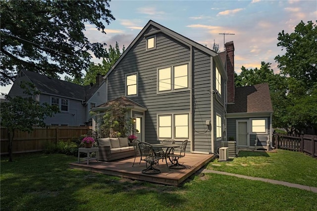 611 E 64th Ter, Kansas City, MO 64131 - back of house at dusk with a fenced backyard, a chimney, and a deck