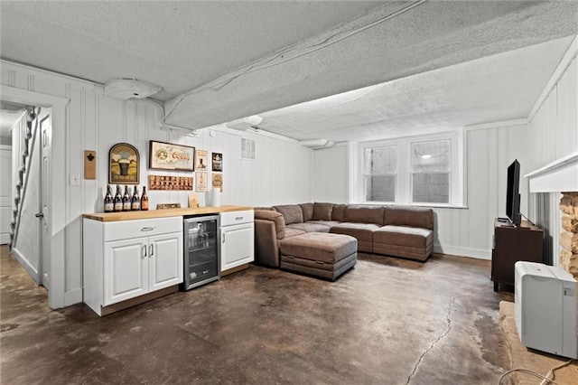 611 E 64th Ter, Kansas City, MO 64131 - indoor dry bar featuring wine cooler, concrete flooring, a decorative wall, and a textured ceiling
