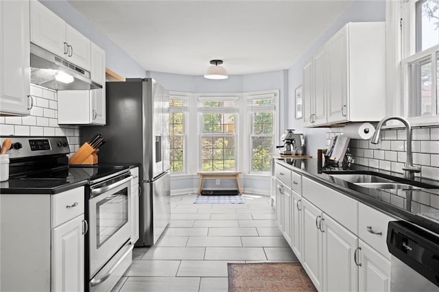 611 E 64th Ter, Kansas City, MO 64131 - kitchen featuring stainless steel appliances, under cabinet range hood, dark countertops, and healthy amount of natural light