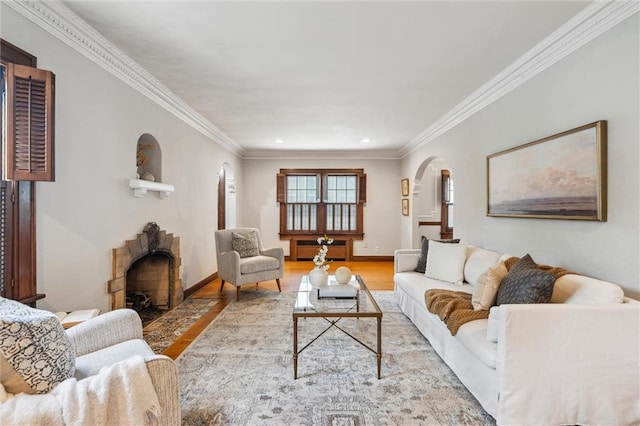 6661 Locust St, Kansas City, MO 64131 - living area featuring arched walkways, wood finished floors, a fireplace with flush hearth, ornamental molding, and baseboards