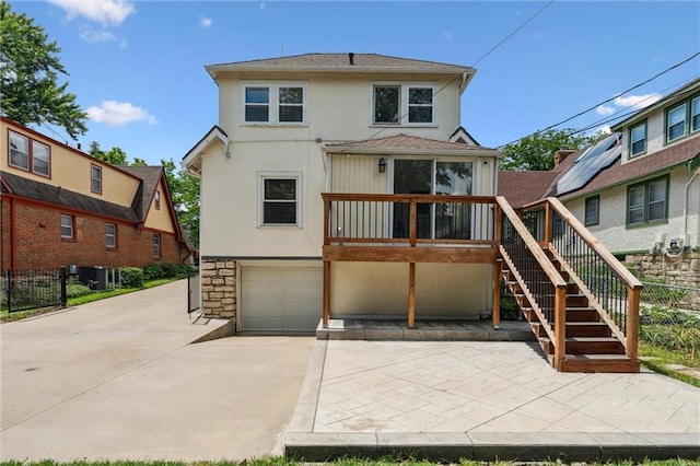 6661 Locust St, Kansas City, MO 64131 - rear view of house featuring stucco siding, stairs, a garage, concrete driveway, and stone siding