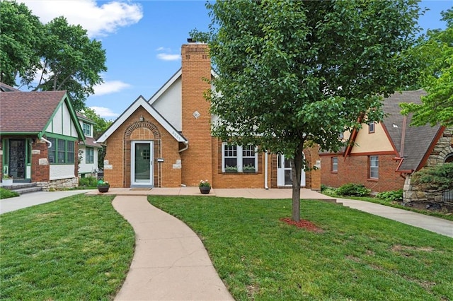 6661 Locust St, Kansas City, MO 64131 - tudor-style house with a front lawn, a chimney, and brick siding
