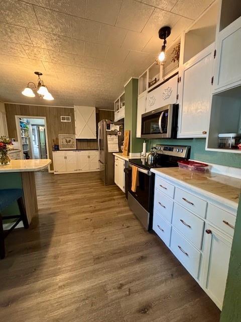 217 5th St, Burlington, KS 66839 - kitchen featuring appliances with stainless steel finishes, white cabinetry, dark wood-type flooring, a chandelier, and open shelves