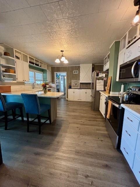 217 5th St, Burlington, KS 66839 - kitchen with stainless steel appliances, open shelves, light countertops, dark wood-style floors, and a chandelier