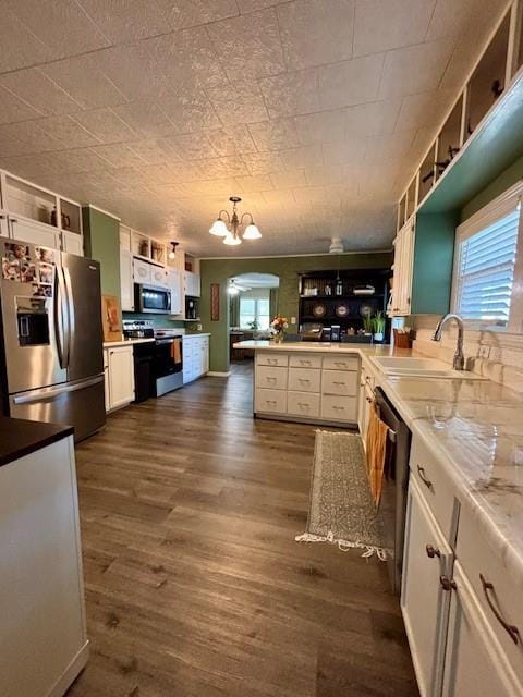217 S 5th St, Burlington, KS 66839 - kitchen featuring appliances with stainless steel finishes, a peninsula, dark wood-style floors, a chandelier, and white cabinets