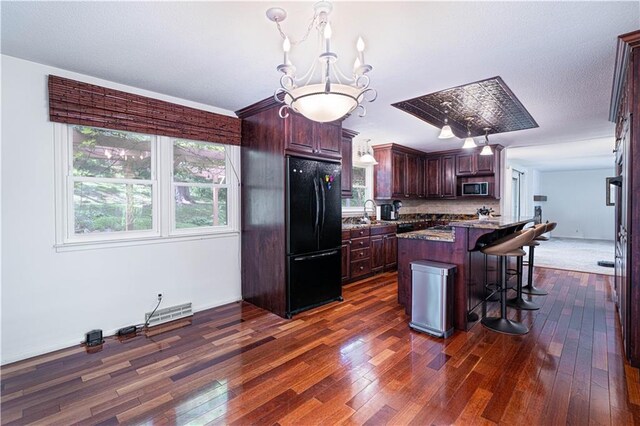 2002 N 29th St, Saint Joseph, MO 64506 - kitchen with freestanding refrigerator, stainless steel microwave, dark wood-type flooring, and a center island