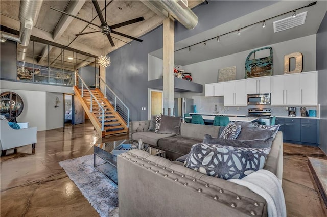 360 W Pershing Rd Unit 310, Kansas City, MO 64108 - living area featuring finished concrete floors, a towering ceiling, stairs, and ceiling fan