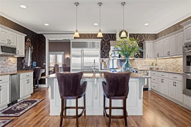 14971 Fairmount Rd, Basehor, KS 66007 - kitchen featuring stainless steel appliances, wood finished floors, backsplash, ornamental molding, and wallpapered walls
