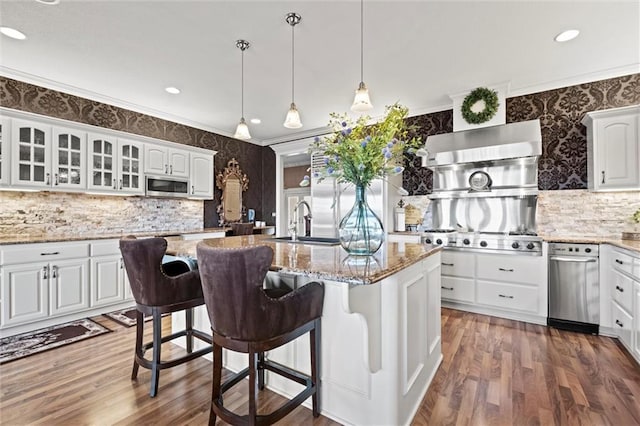 14971 Fairmount Rd, Basehor, KS 66007 - kitchen featuring stainless steel microwave, backsplash, an island with sink, white cabinets, and glass insert cabinets