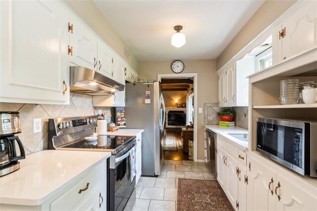 9613 Dearborn St, Overland Park, KS 66207 - kitchen featuring under cabinet range hood, stainless steel appliances, white cabinets, tasteful backsplash, and light countertops