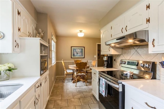 9613 Dearborn St, Overland Park, KS 66207 - kitchen featuring electric stove, under cabinet range hood, white cabinets, tasteful backsplash, and wainscoting