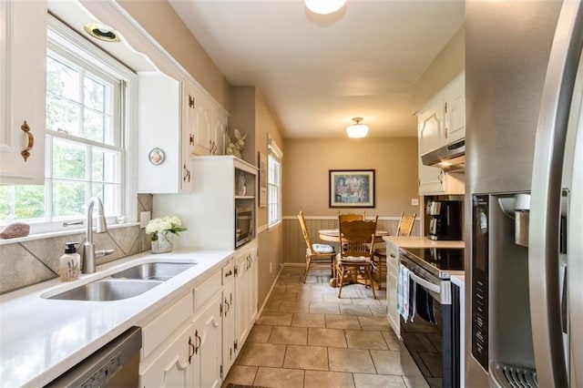 9613 Dearborn St, Overland Park, KS 66207 - kitchen with appliances with stainless steel finishes, a sink, white cabinetry, light countertops, and wainscoting