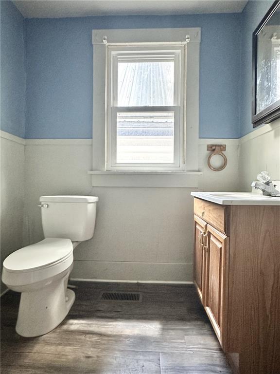 206 S Main St, Trenton, MO 64683 - bathroom featuring toilet, wood finished floors, vanity, a wainscoted wall, and baseboards