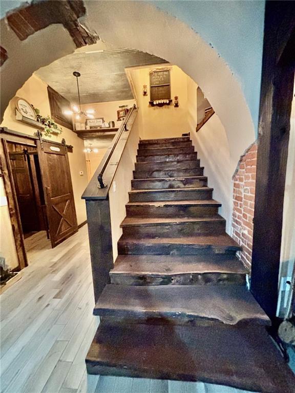 115 N 3rd St, Burlington, KS 66839 - stairway featuring wood finished floors, a barn door, and arched walkways