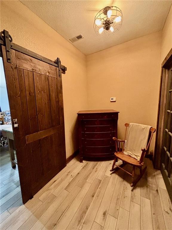 115 N 3rd St, Burlington, KS 66839 - living area featuring light wood-style flooring, a barn door, and a textured ceiling