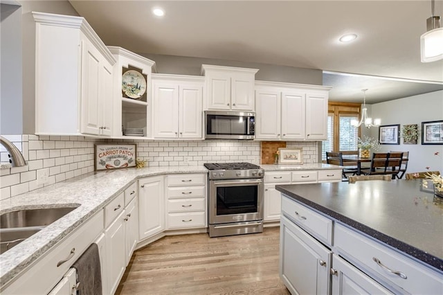 5204 W 166th St, Overland Park, KS 66085 - kitchen featuring stainless steel appliances, a sink, white cabinets, a chandelier, and light wood-style flooring