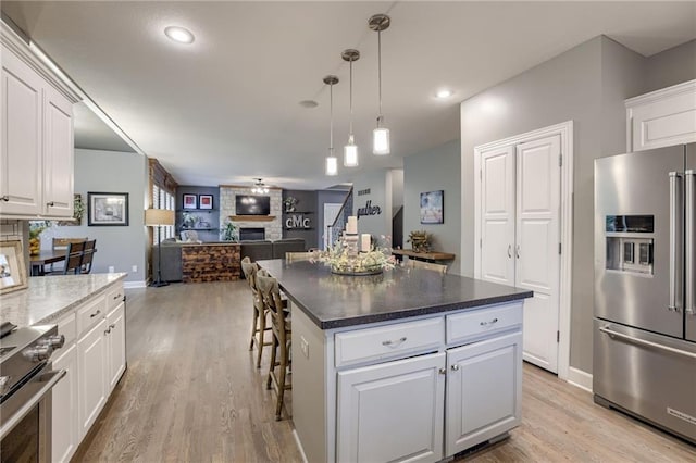 5204 W 166th St, Overland Park, KS 66085 - kitchen featuring stainless steel appliances, a fireplace, light wood-style flooring, open floor plan, and recessed lighting