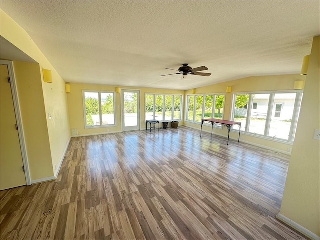 17795 K Hwy, Saint Joseph, MO 64505 - unfurnished living room with a textured ceiling, baseboards, vaulted ceiling, wood finished floors, and a ceiling fan
