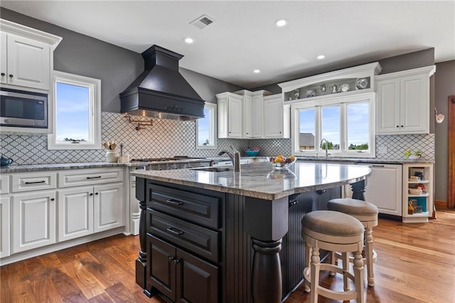 15405 161st St, Bonner Springs, KS 66012 - kitchen featuring custom exhaust hood, stainless steel microwave, dishwashing machine, white cabinetry, and recessed lighting