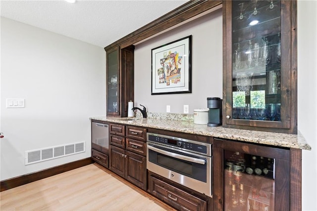 15405 161st St, Bonner Springs, KS 66012 - indoor wet bar with beverage cooler, oven, light wood-style flooring, and a textured ceiling