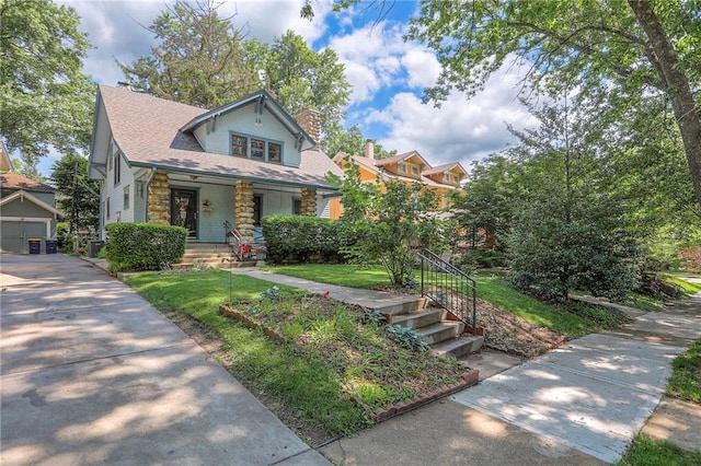 12 W 57th Ter, Kansas City, MO 64113 - view of front of house featuring stone siding, a chimney, covered porch, a front lawn, and an outbuilding