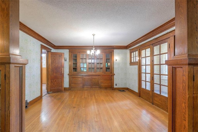 12 W 57th Ter, Kansas City, MO 64113 - unfurnished dining area featuring crown molding, light wood finished floors, a chandelier, a textured ceiling, and french doors