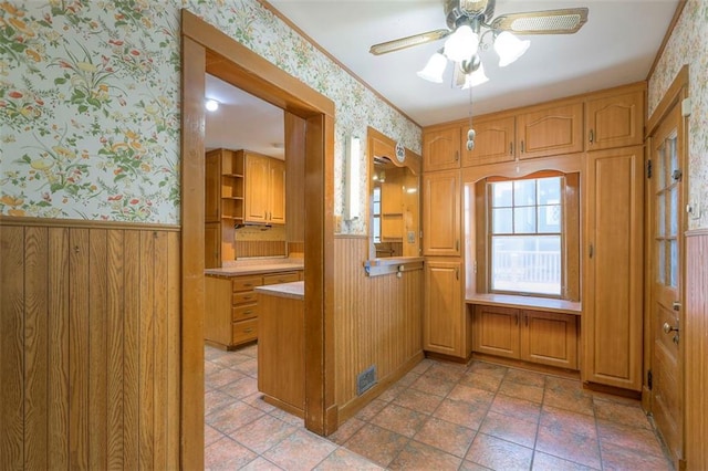 12 W 57th Ter, Kansas City, MO 64113 - kitchen with wallpapered walls, a wainscoted wall, ceiling fan, wooden walls, and light countertops