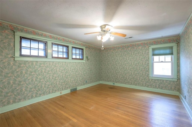 12 W 57th Ter, Kansas City, MO 64113 - unfurnished room featuring plenty of natural light, wood finished floors, a ceiling fan, and wallpapered walls