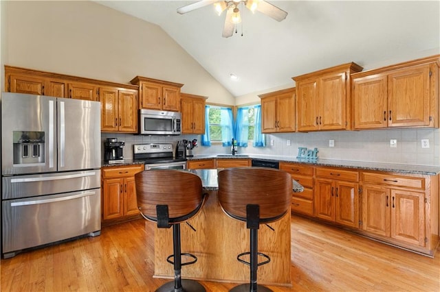 3223 SW Amber Ct, Lees Summit, MO 64082 - kitchen with stainless steel appliances, a sink, brown cabinets, light wood-style flooring, and high vaulted ceiling